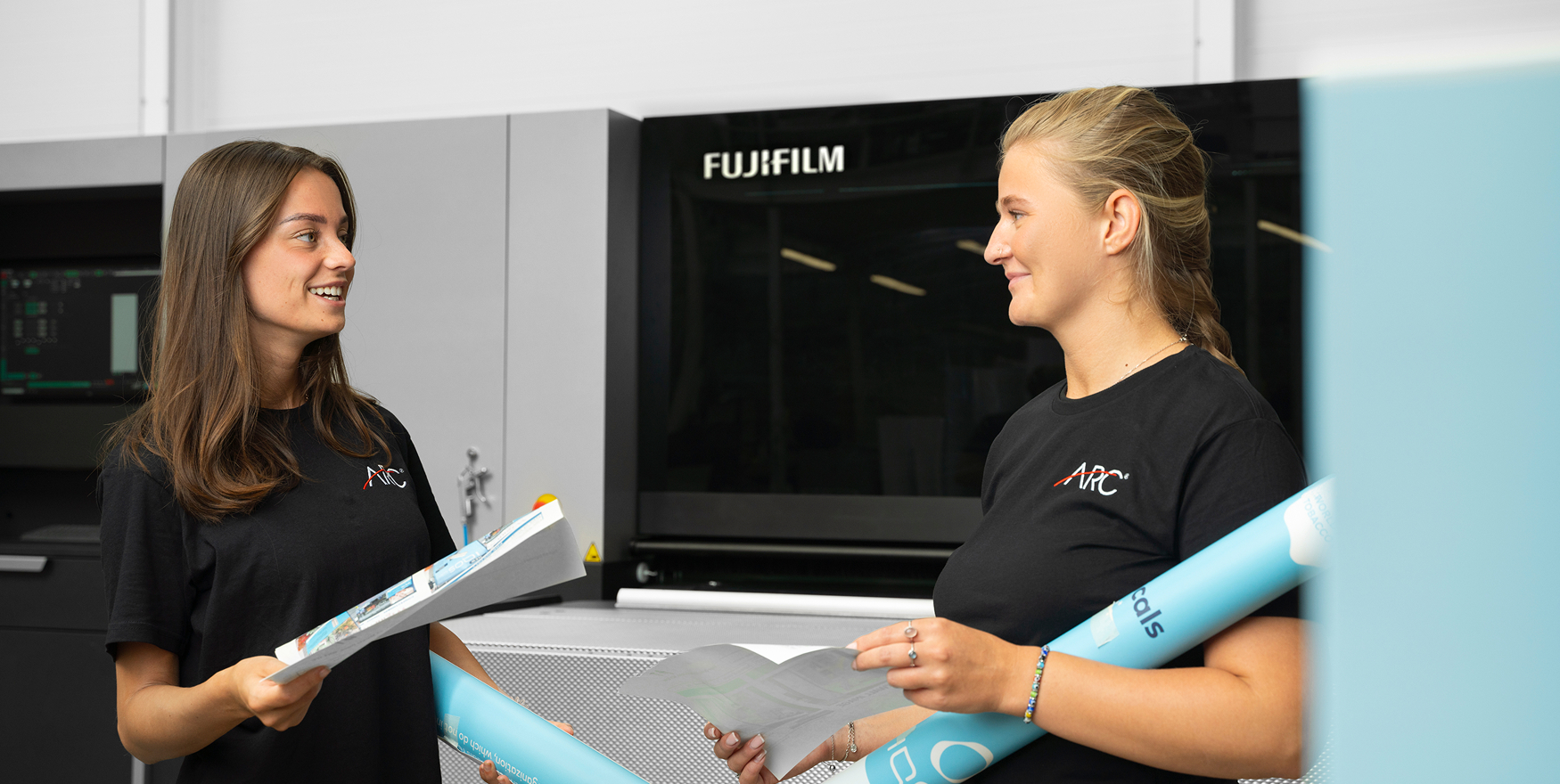ARC UK team members discussing printed graphics beside a large format printer